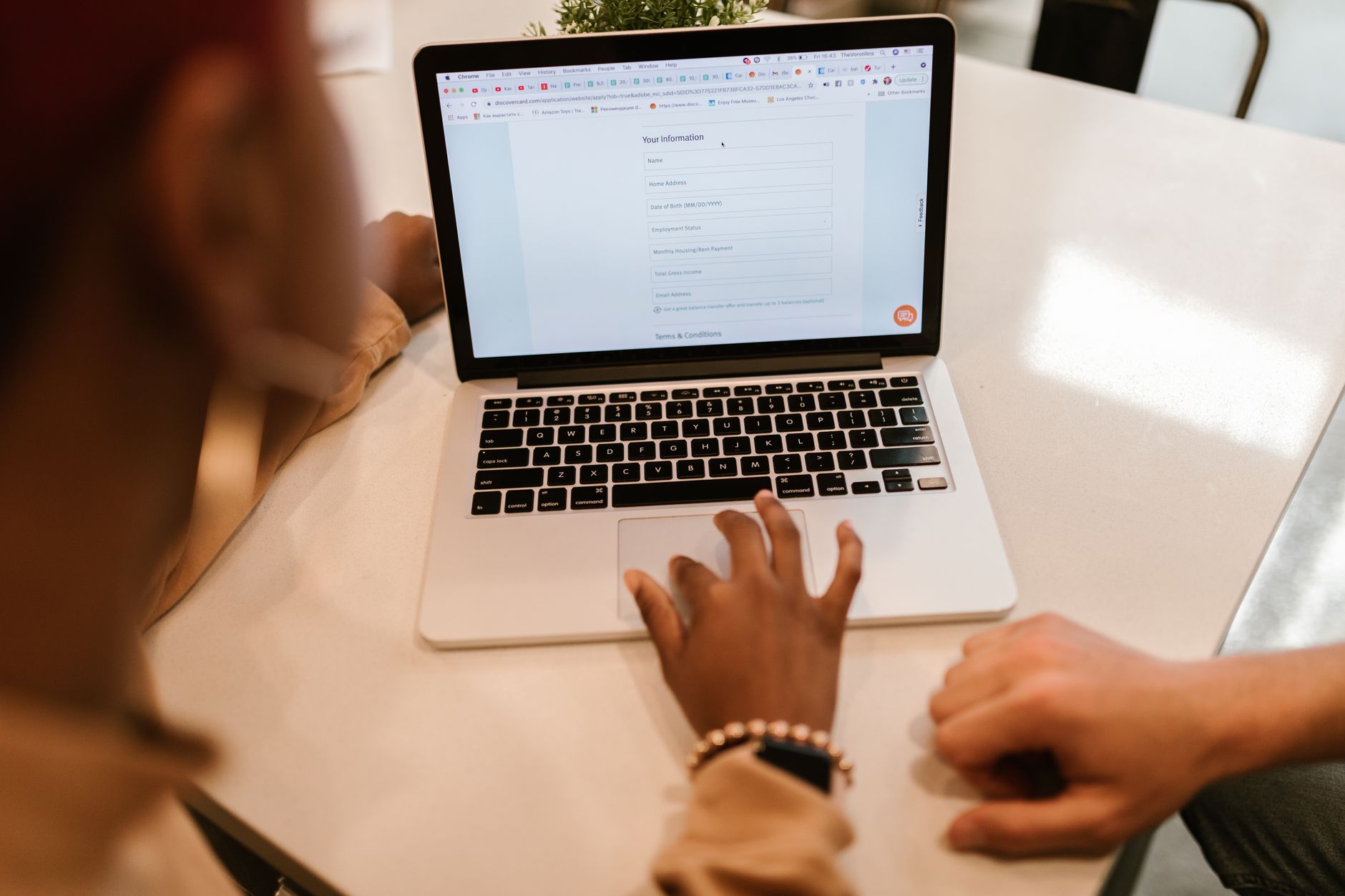 A person's hand enters personal data into an online form on a laptop screen