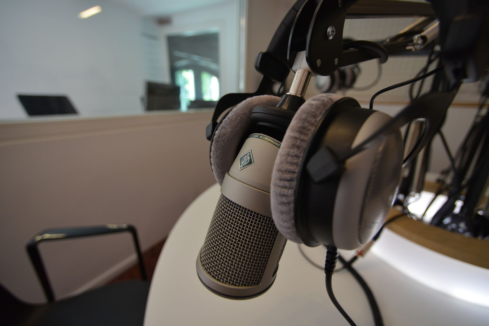 A studio microphone with over-ear headphones in a podcast recording space