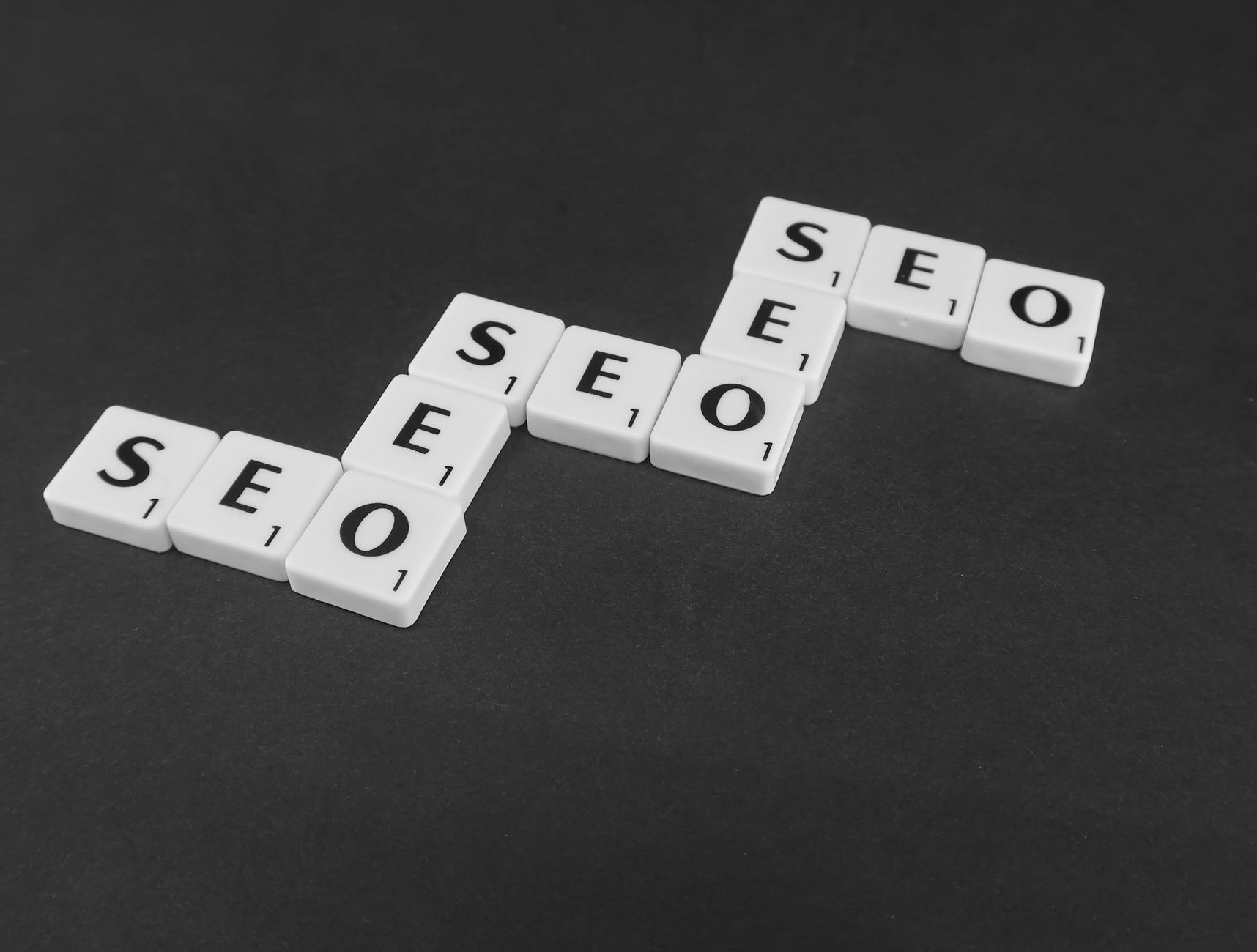 White Scrabble-like tiles spell "SEO" repeatedly, illustrating search engine optimization efforts