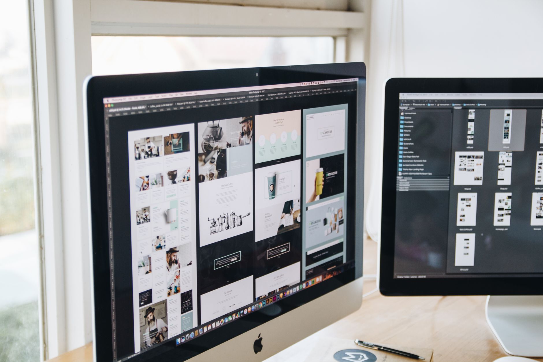 Two monitors display web design layouts and file directories for SEO software