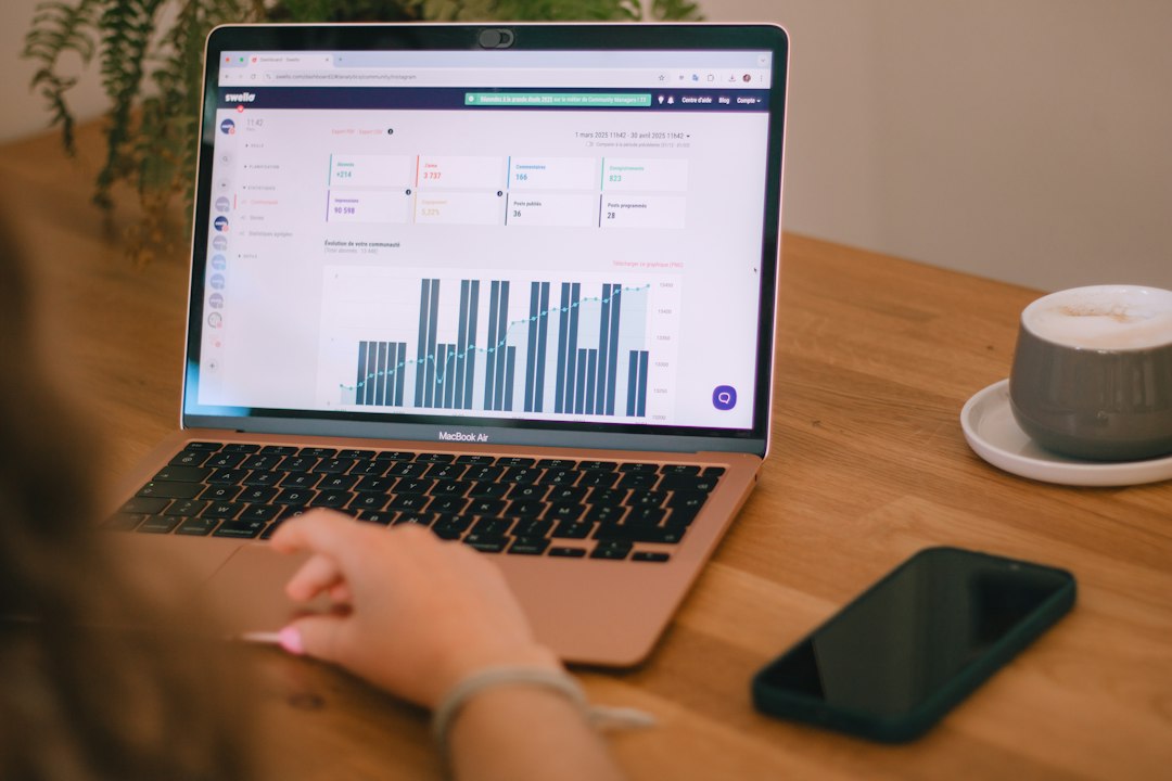 An open laptop displaying an analytics dashboard sits on a wooden desk