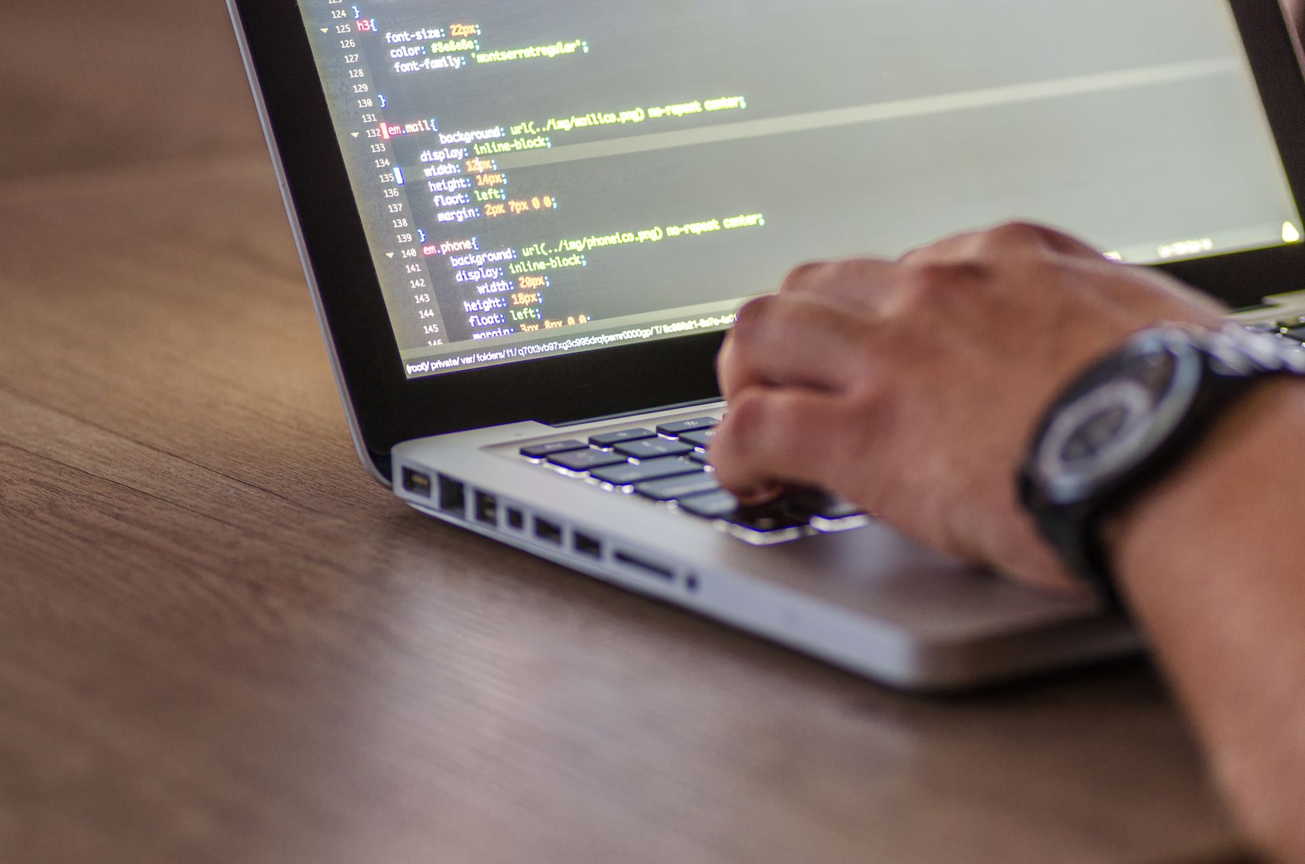Hands typing code on a laptop screen, depicting web application development