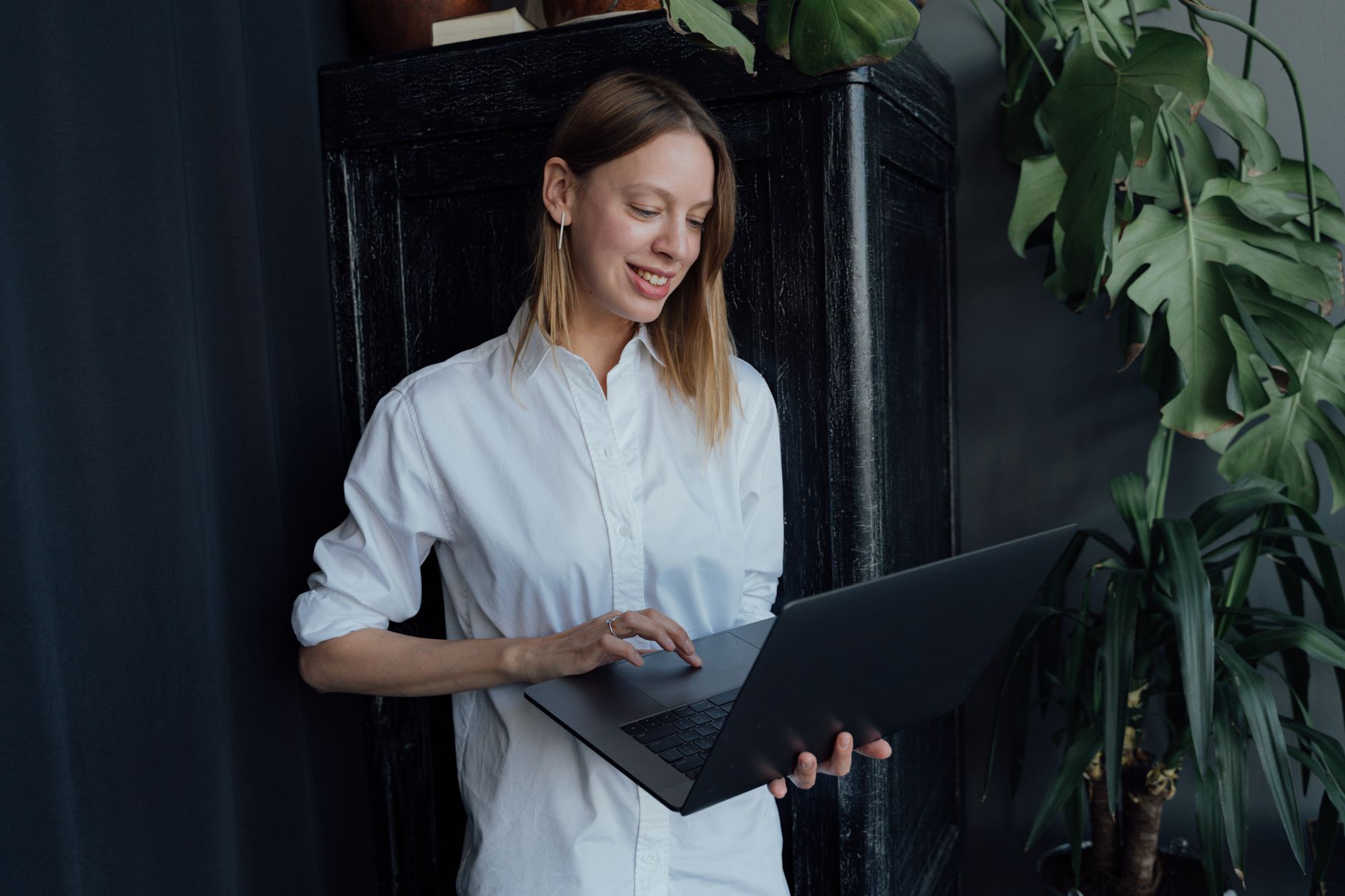Smiling woman in a white shirt uses a laptop, likely for affordable e-commerce SEO