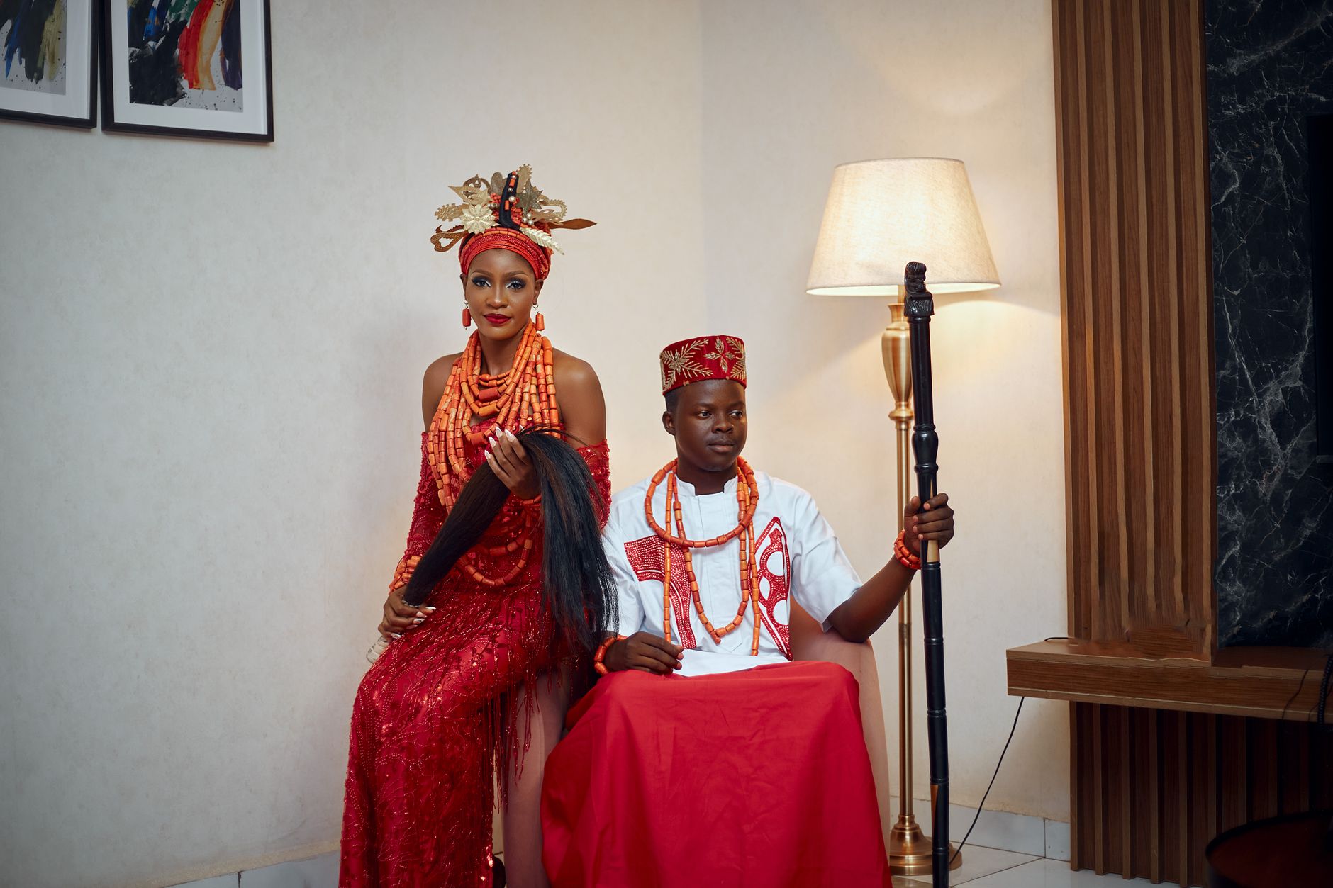 Couple in traditional Nigerian wedding attire posing indoors with coral beads