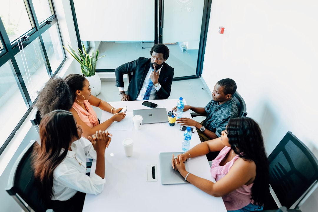 Five diverse professionals discussing commercial relationships at a modern conference table