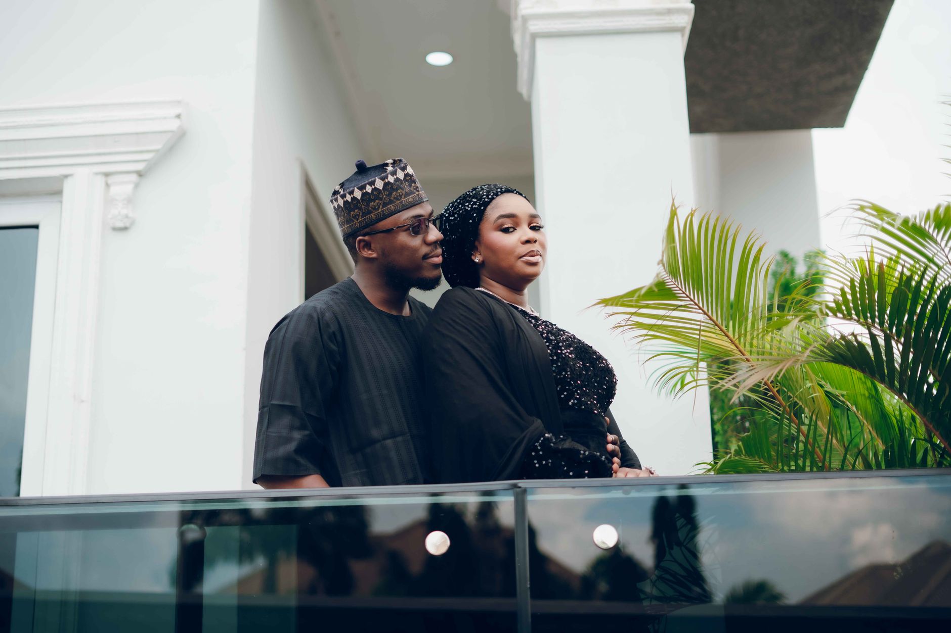 Couple in traditional black attire standing on a modern building's balcony