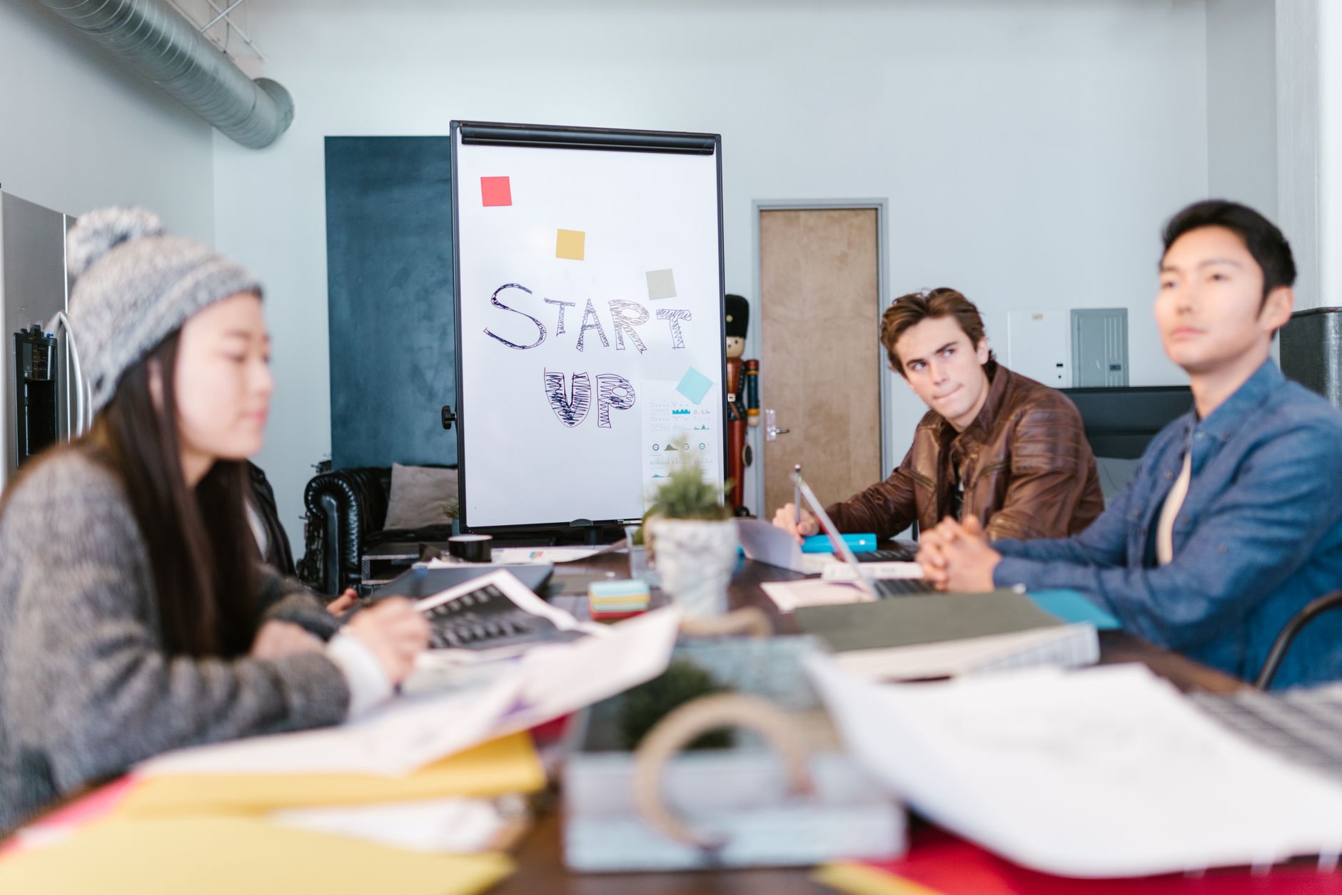 Young professionals at a table collaborating on a "START UP" project, discussing digital services