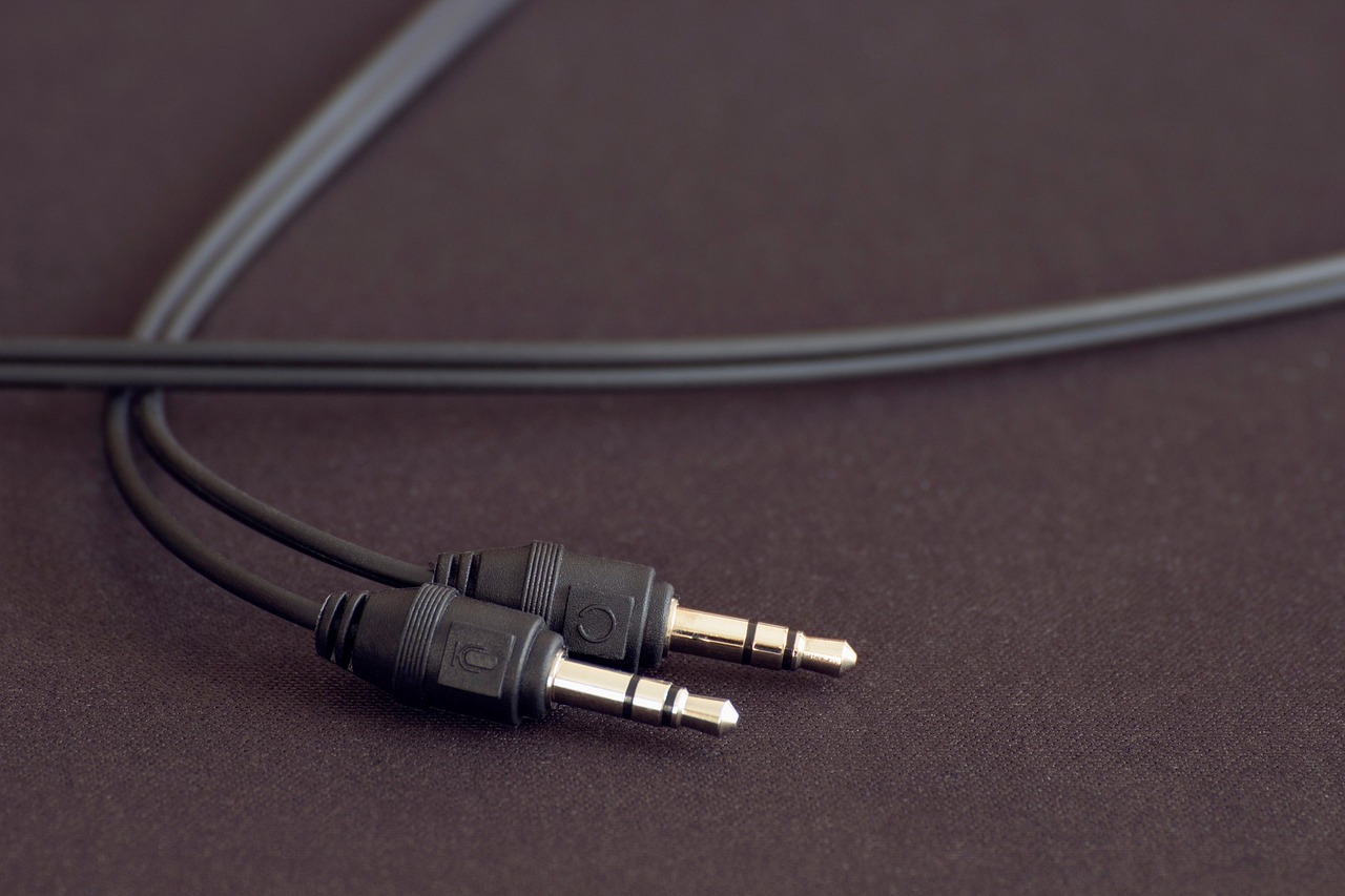 Two audio jack cables on a dark surface, symbolizing podcast prerequisites