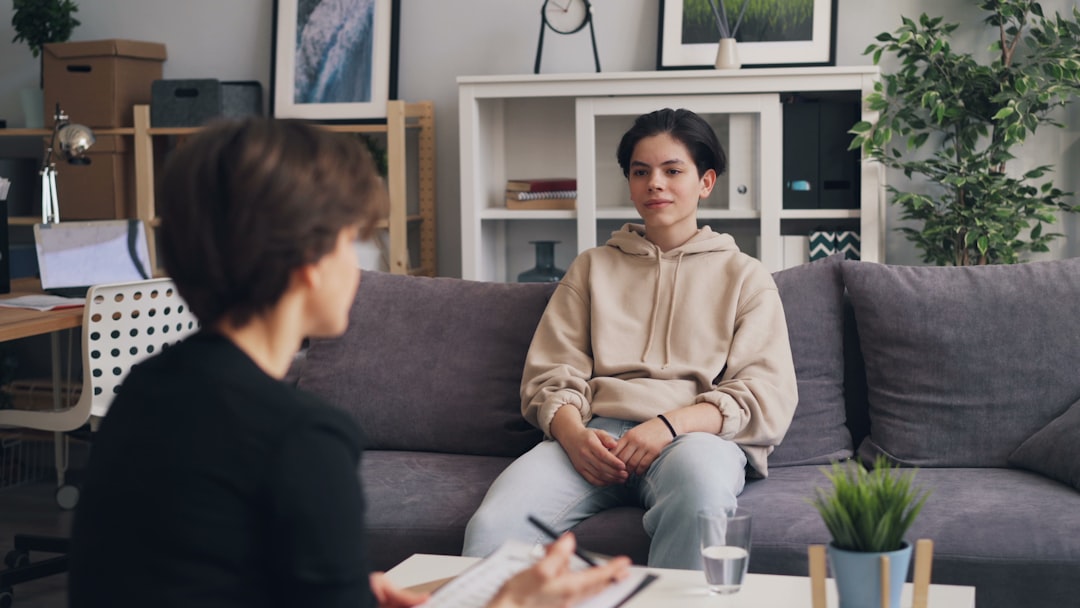 A therapist listens to a young person sitting on a comfortable couch