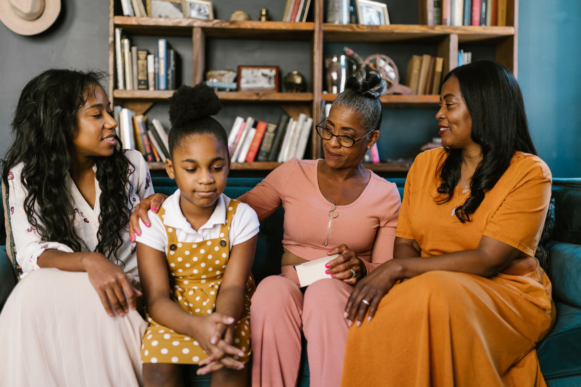 Four Black females of different generations sharing a close, supportive moment together