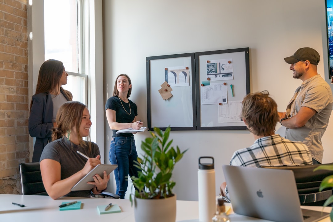 Five startup team members collaborate around a whiteboard in a modern office