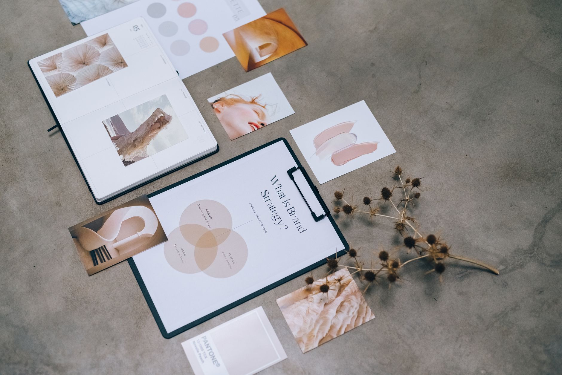A flat lay of brand strategy documents, color swatches, and inspirational photos on a concrete surface