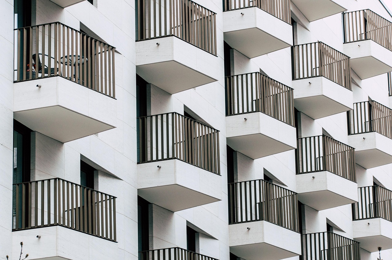 Modern white apartment building exterior with numerous balconies and dark railings