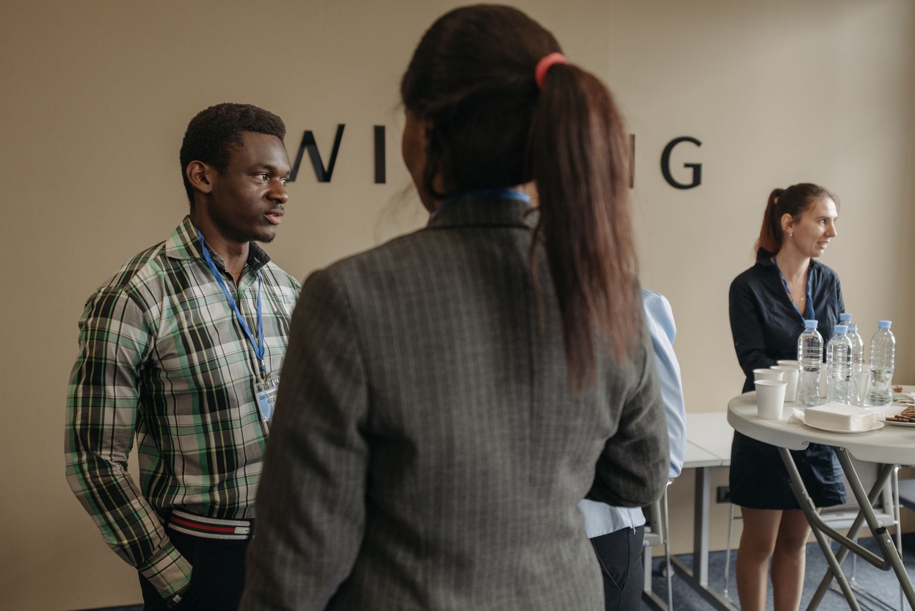 Professionals with name tags networking at a casual event, discussing potential collaborations