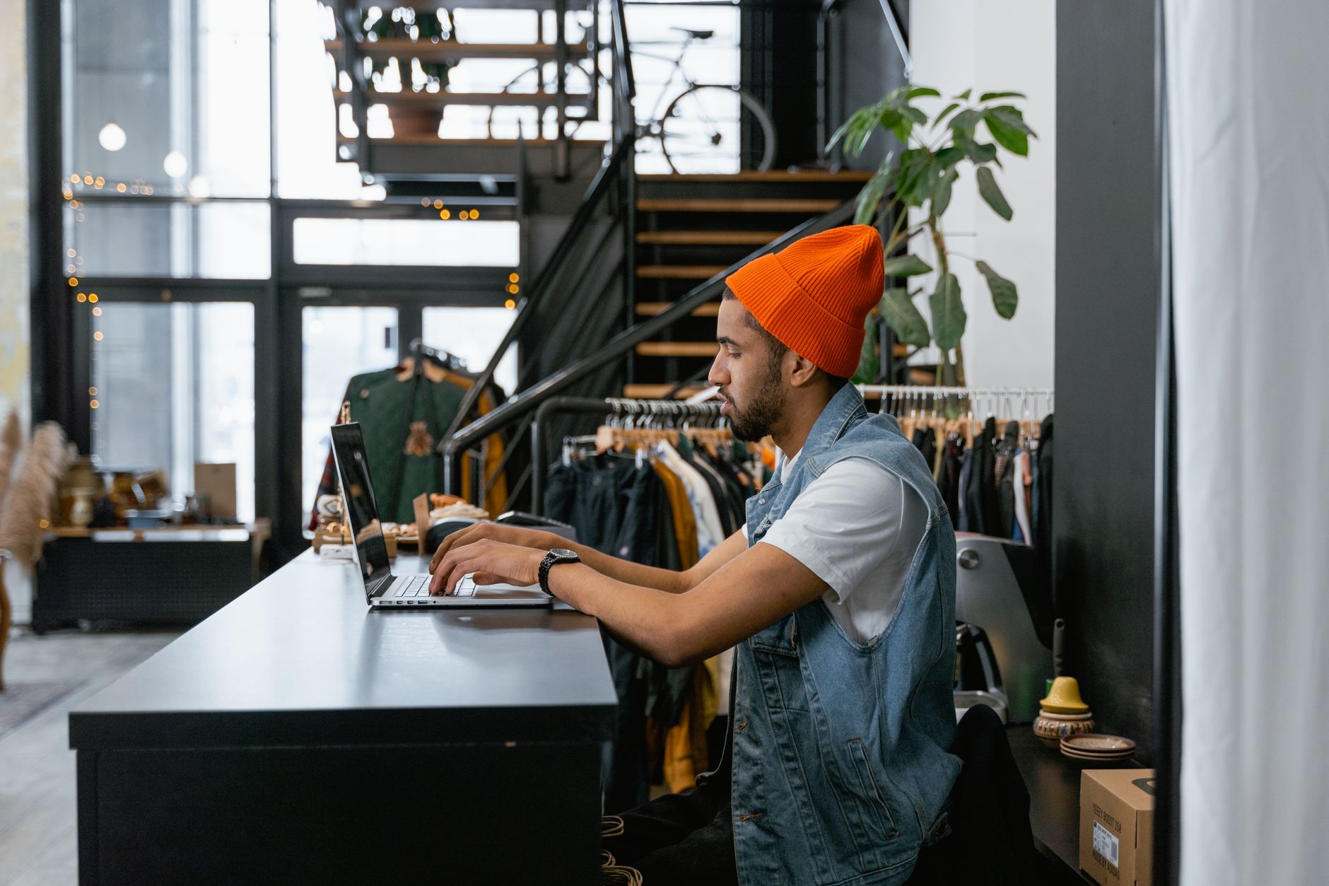 Small business owner working on a laptop inside his modern retail clothing boutique