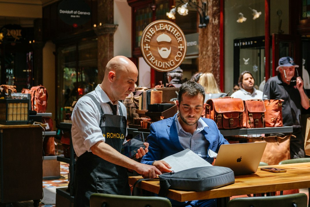 Small leather shop owner reviewing website design options on a laptop with consultant