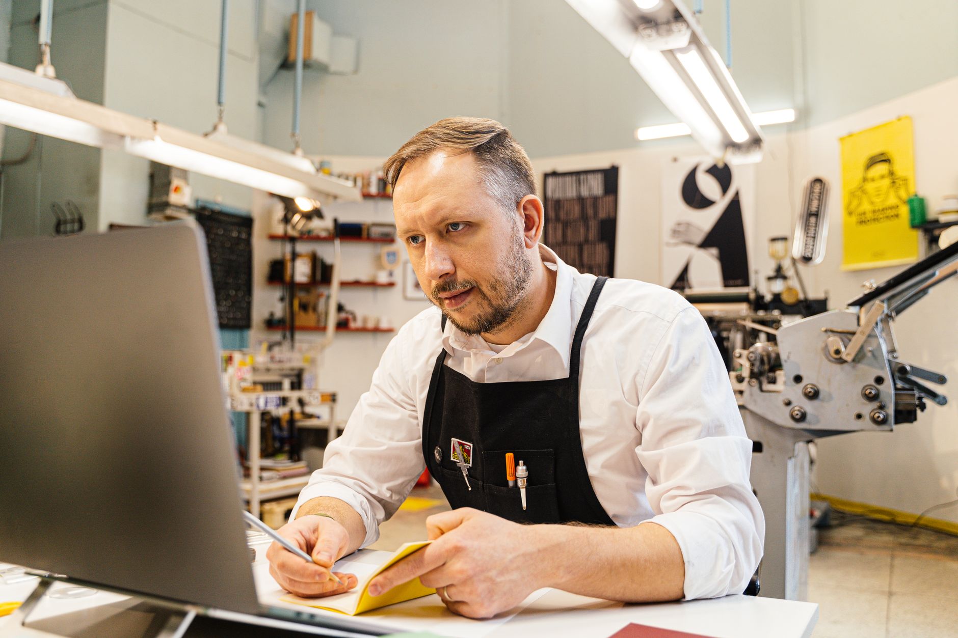 Small business owner takes notes while viewing website design on his laptop