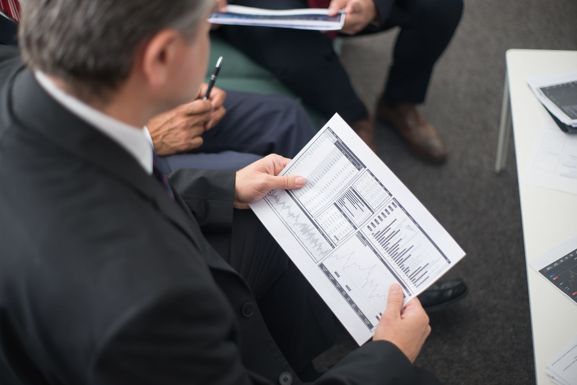 A person in a suit reviews a financial document displaying charts and graphs