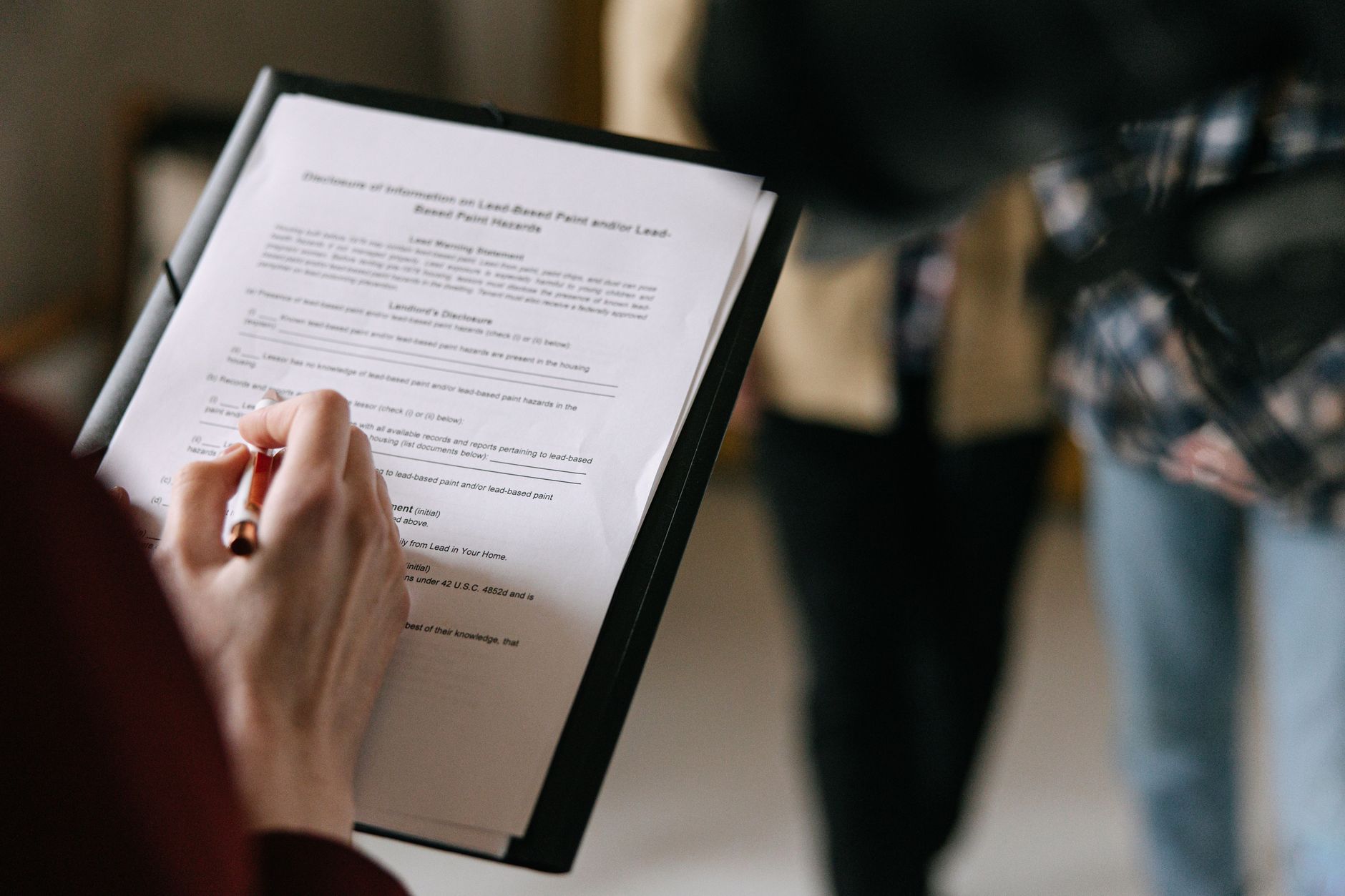 A hand writes on a legal document concerning property disclosure and hazards