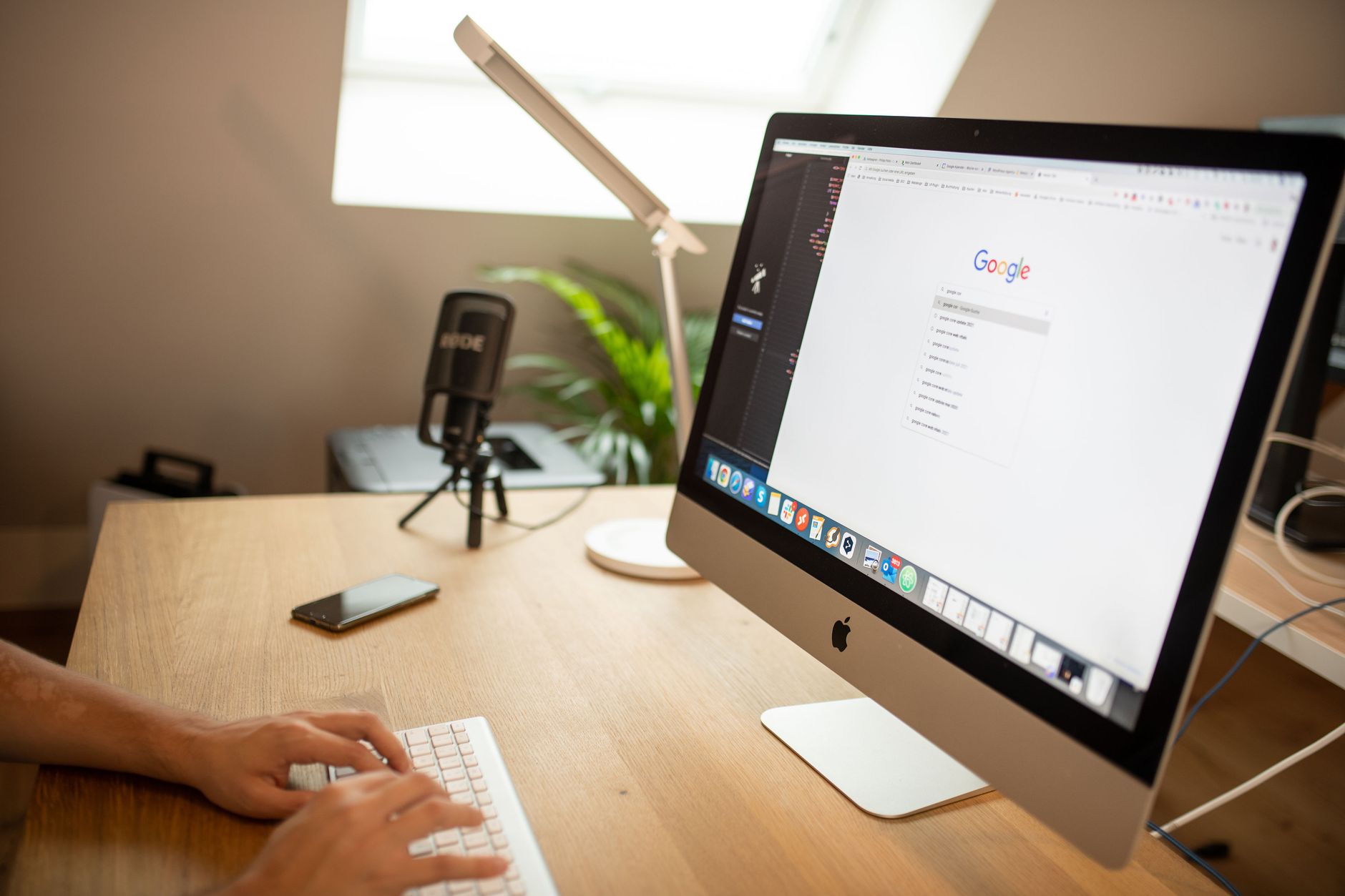 Hands type on a keyboard in front of a computer displaying Google search
