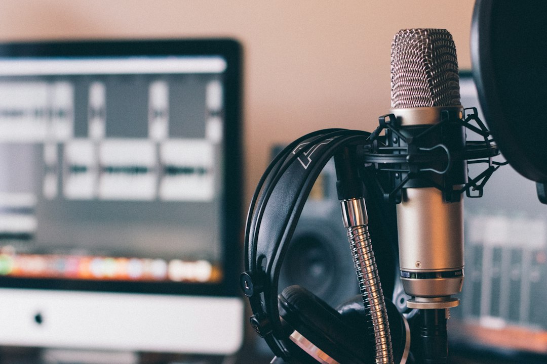 A microphone and headphones stand in front of a monitor showing audio waveforms