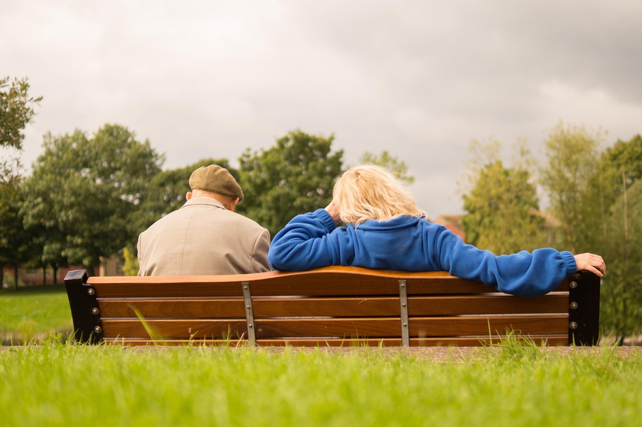 Two elderly guests sit on a comfortable park bench enjoying the outdoors