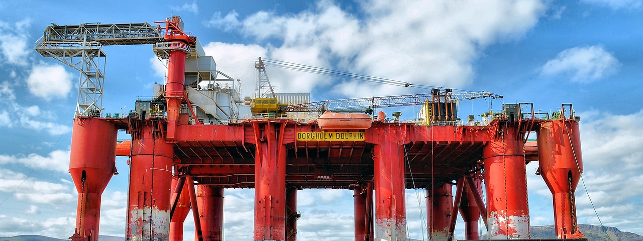Large red Borgolm Dolphin oil exploration platform under a blue, cloudy sky