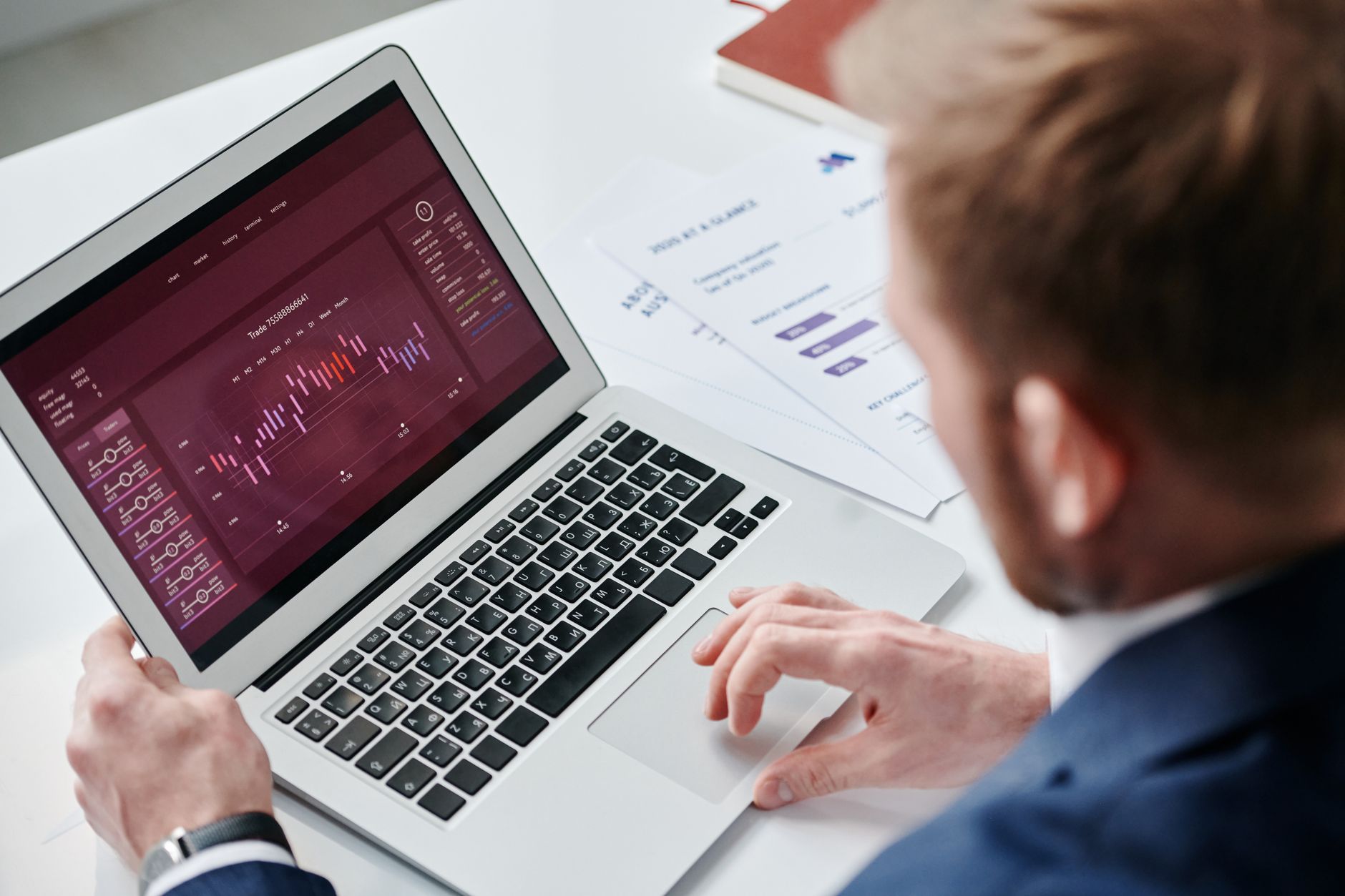A person analyzes data visualizations on a laptop screen, with additional charts nearby