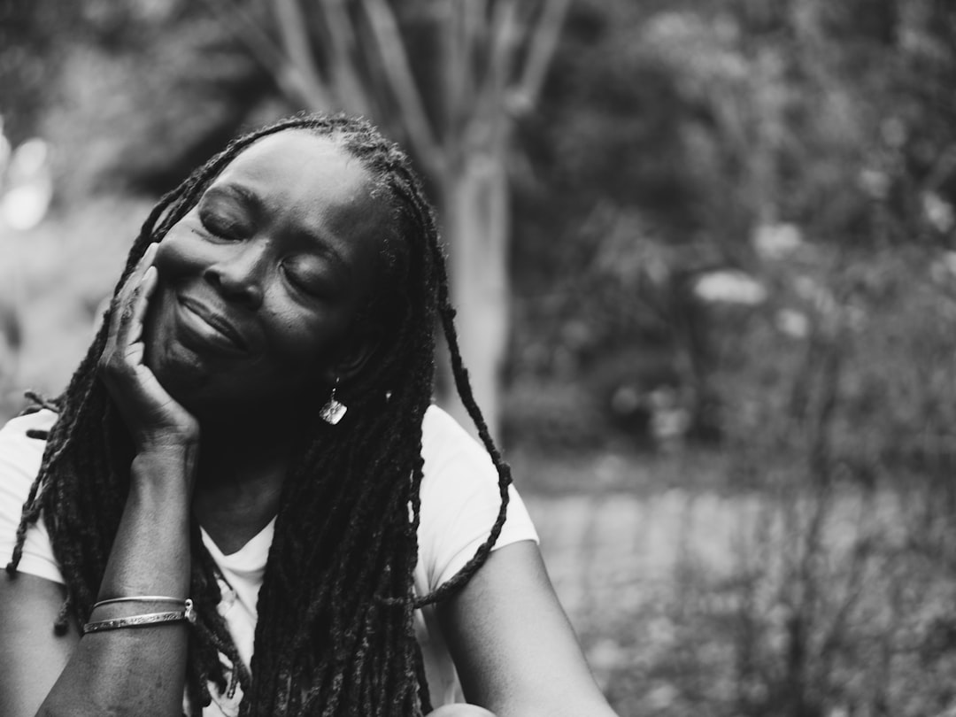 Black and white image of a woman with dreadlocks smiling peacefully, eyes closed