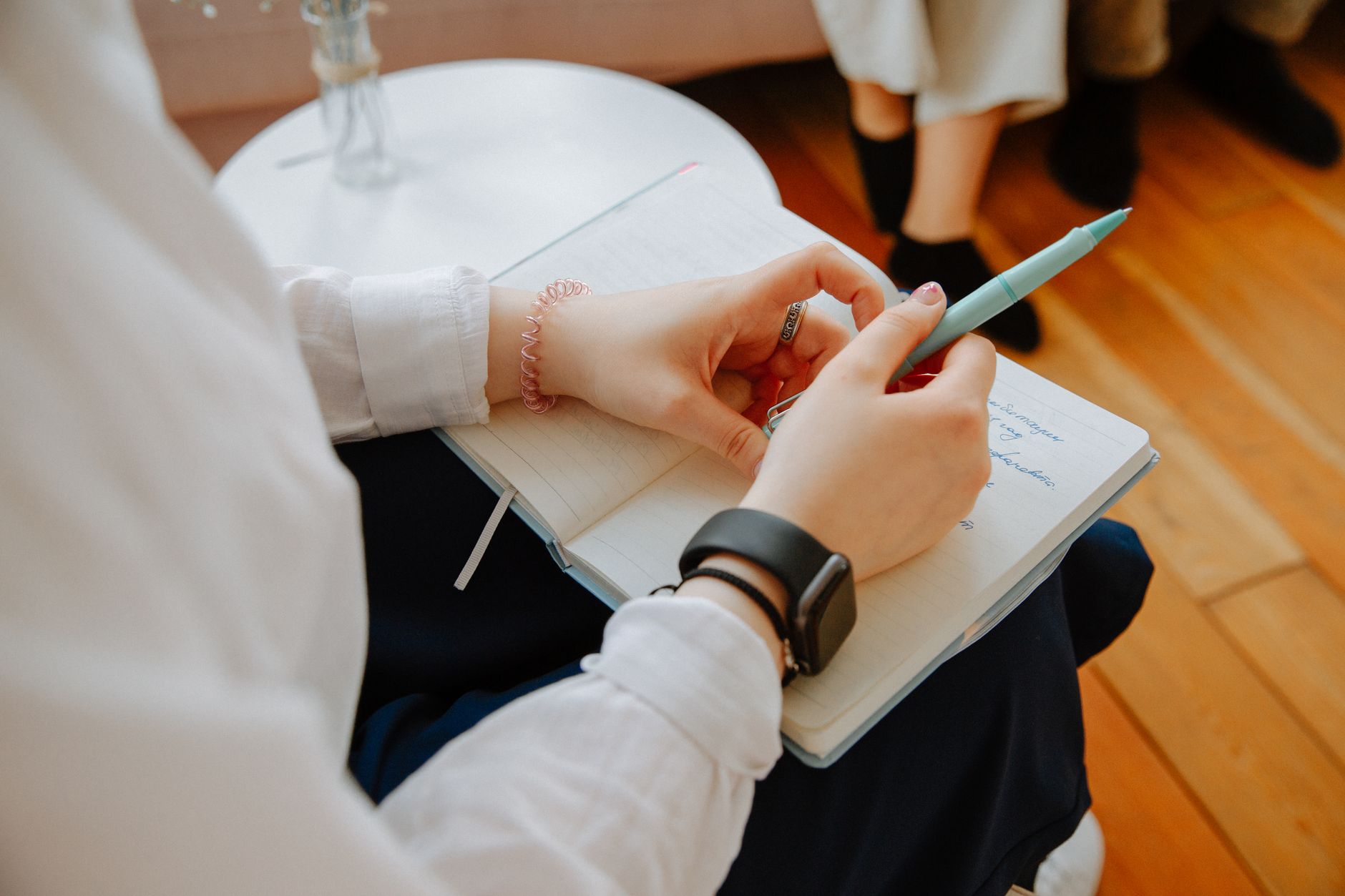 Hands writing in a light blue notebook with a pen, creating content ideas