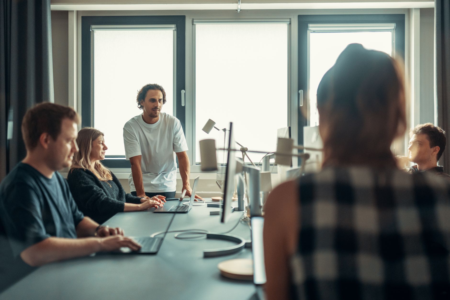 Five people collaborate around a table in an office meeting setting