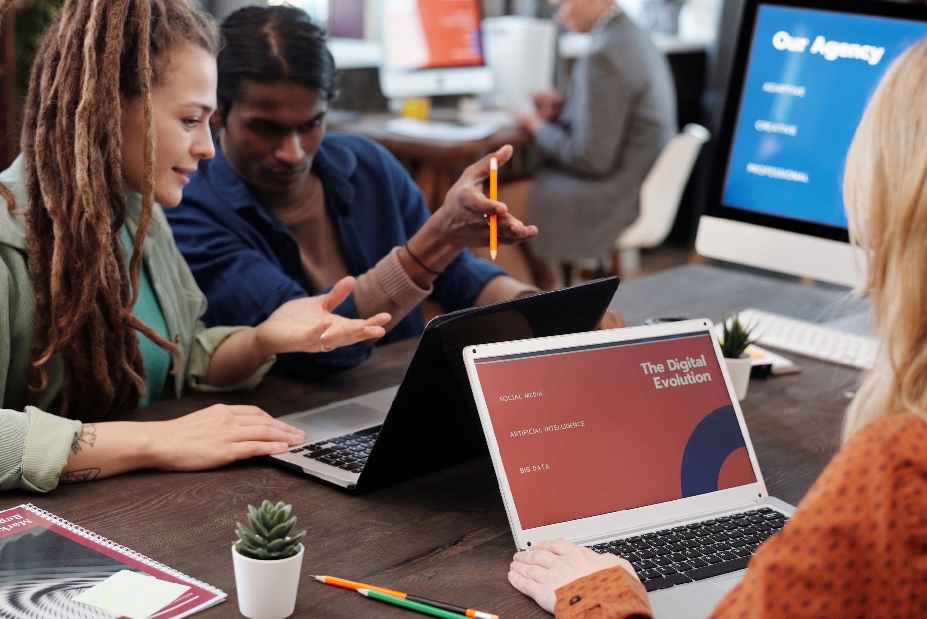 Three people collaborate at a table, discussing content templates for client calendars