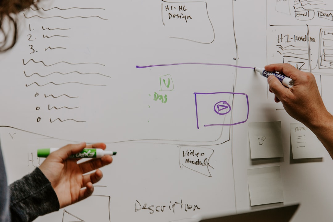Hands drawing and outlining content strategy elements with markers on a whiteboard