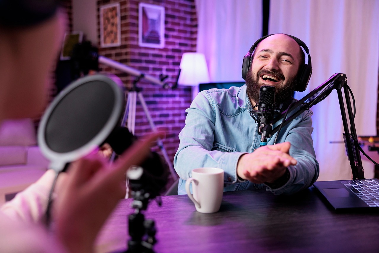Happy podcaster with headphones speaking into a microphone during a recording session