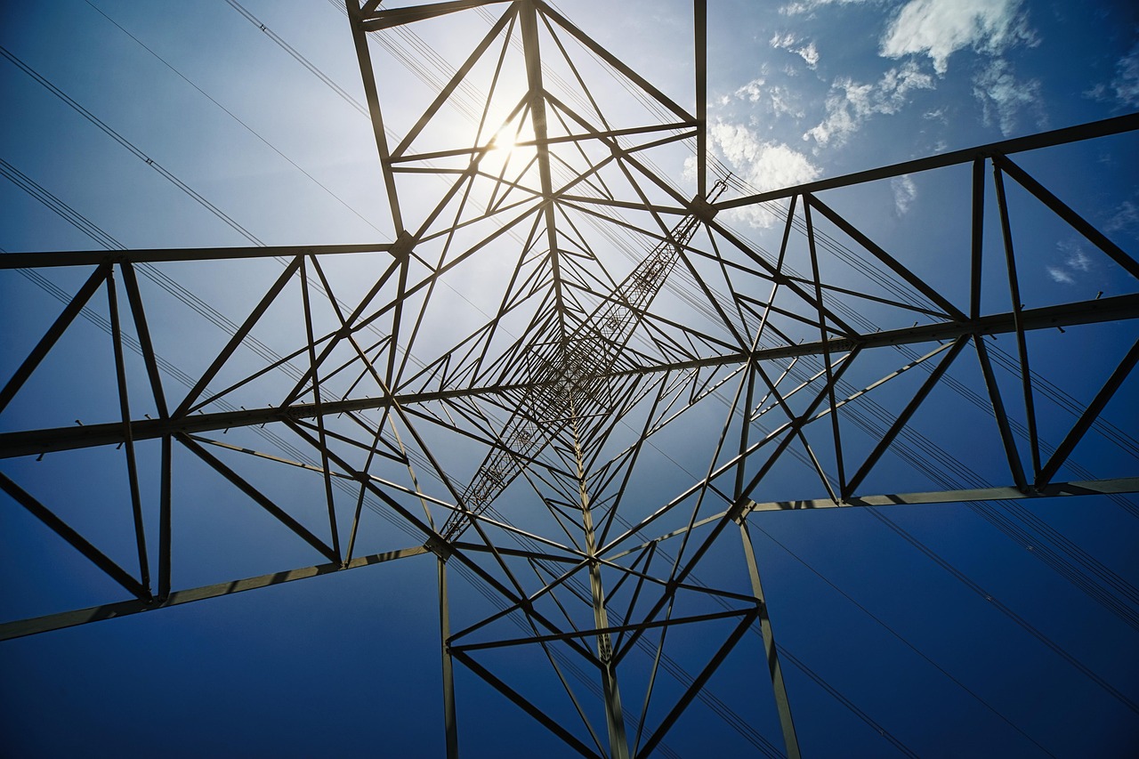 Sunlight shines through the steel lattice structure of an electricity transmission tower