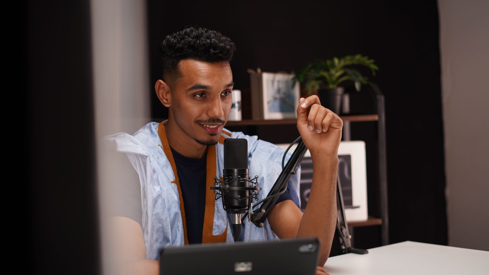 A man speaking into a professional microphone for a podcast recording session