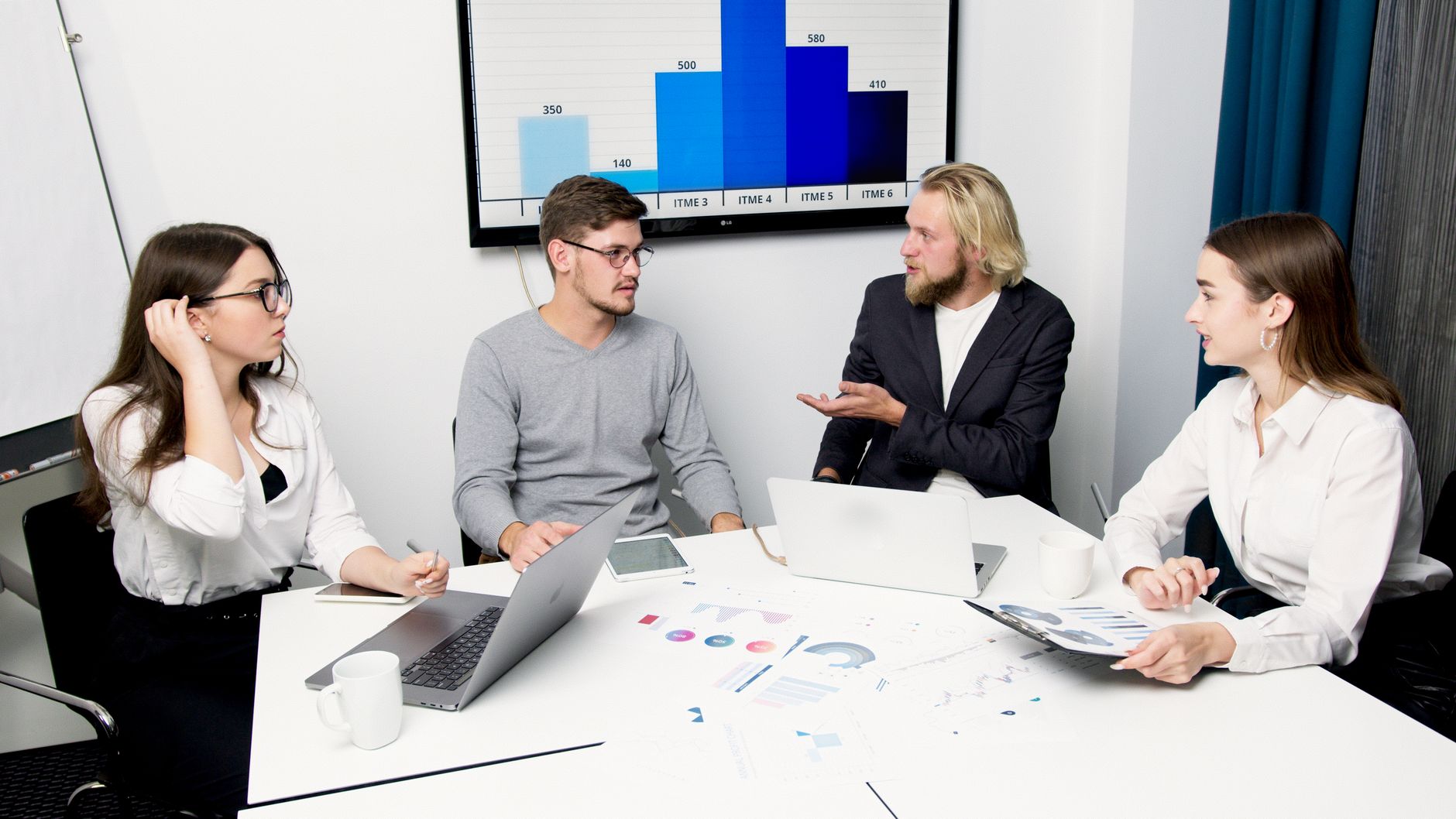 Team meeting discussing data and factors influencing website development costs with charts