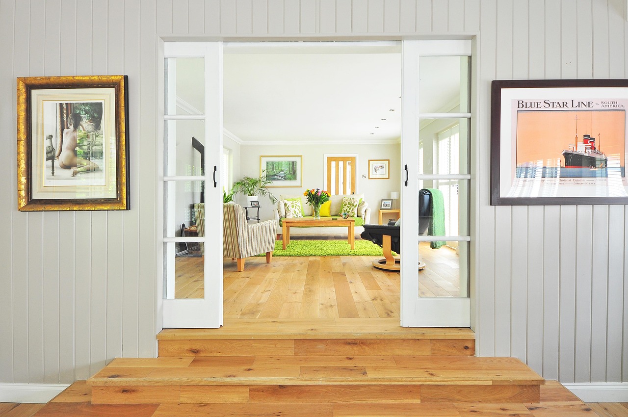 An airy living room with glass doors and wood floors, decorated with houseplants
