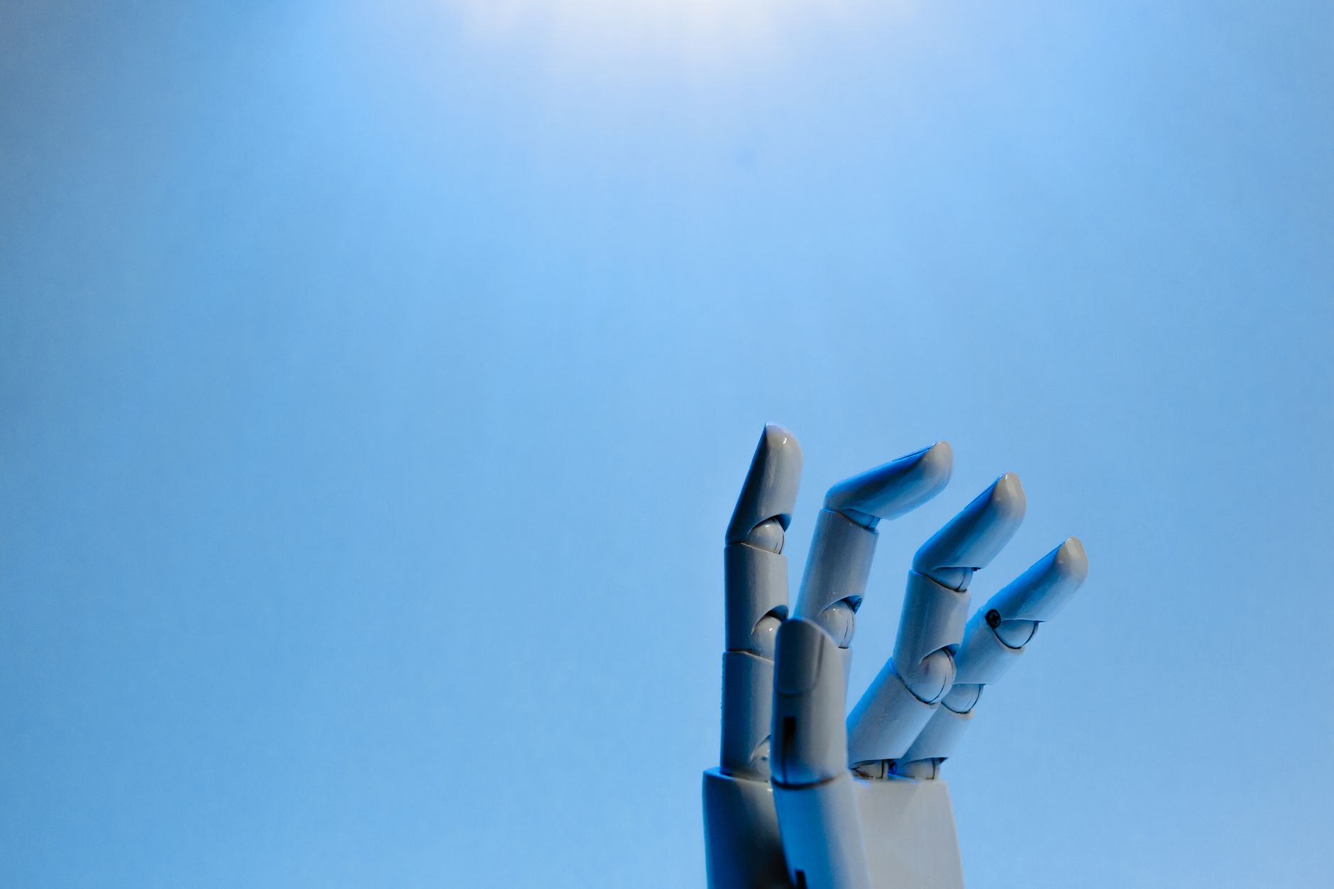 A gray robotic hand with blue light on a light blue background