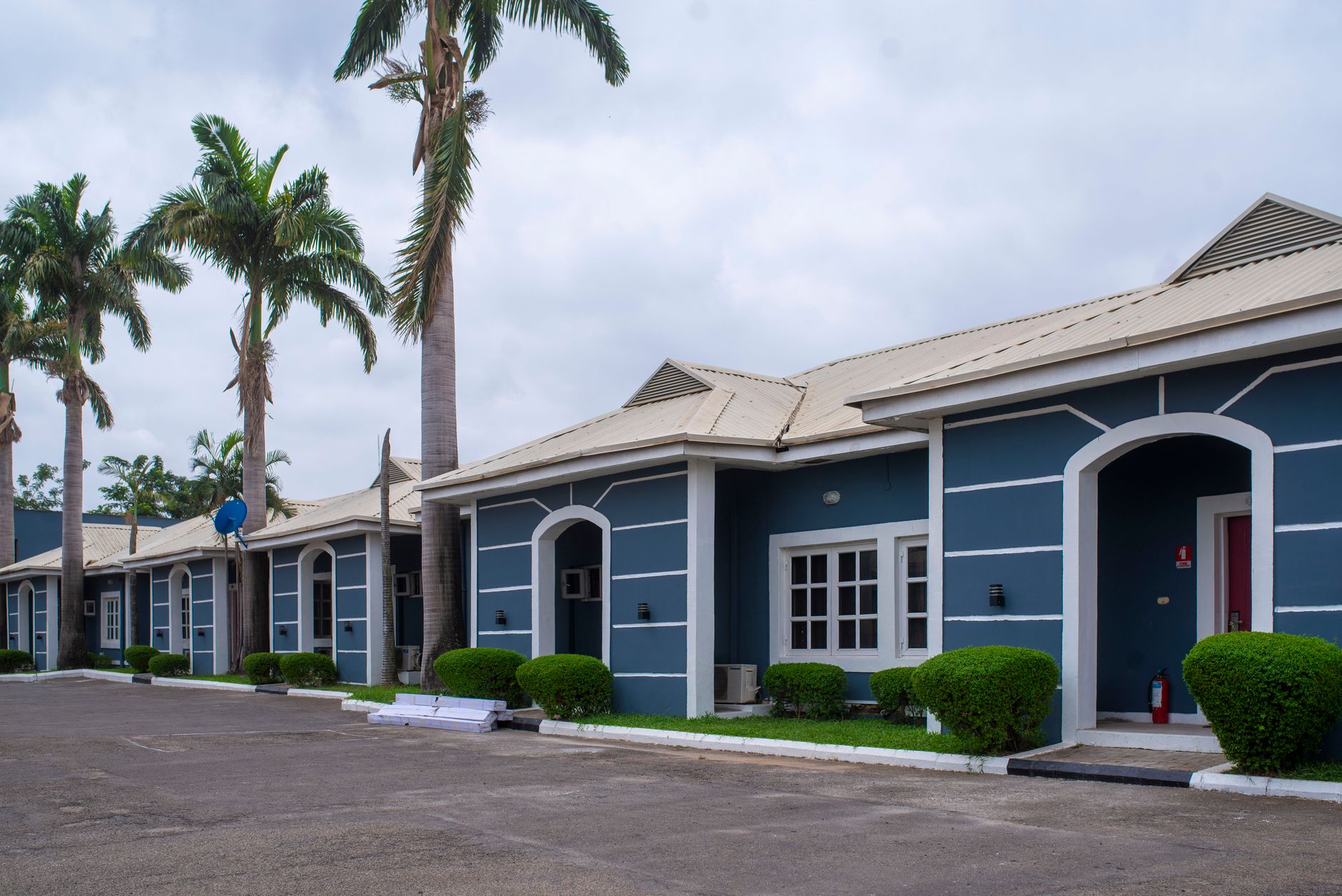 A row of blue and white residential properties in Nigeria under palm trees