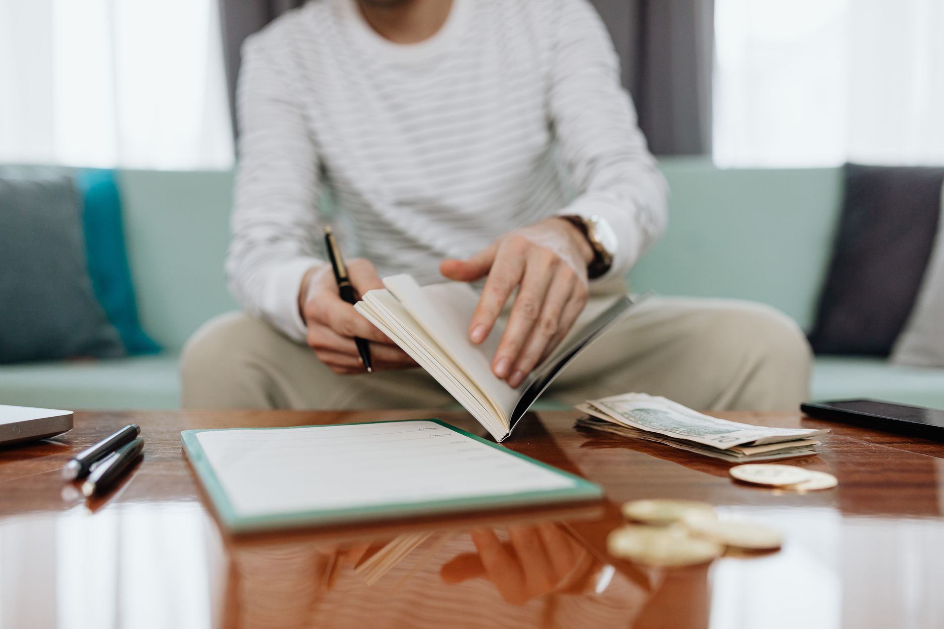 Person budgeting at a table with money, notebook, and pen for SEO costs