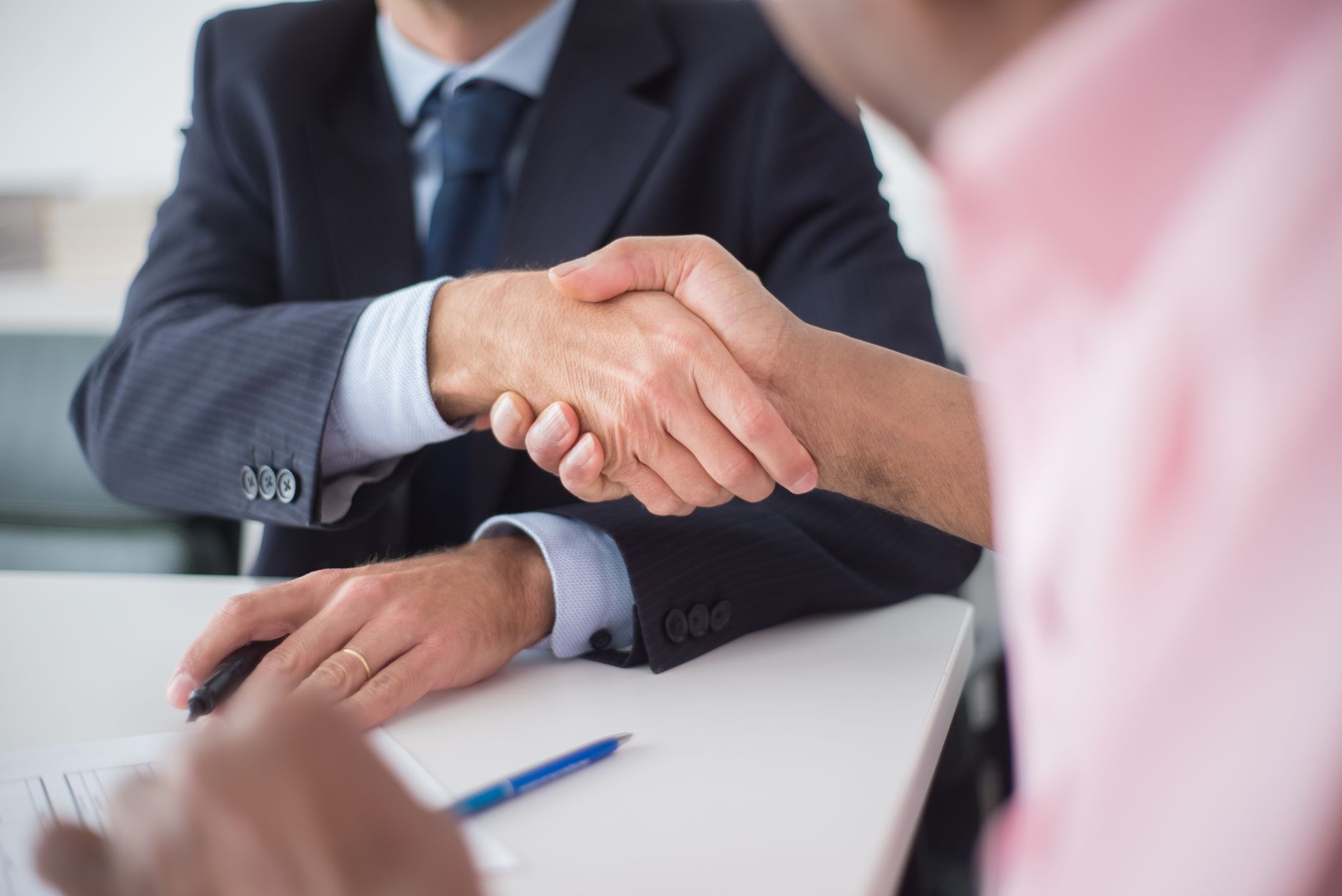 Two people shaking hands across a table, symbolizing a podcast sponsorship agreement