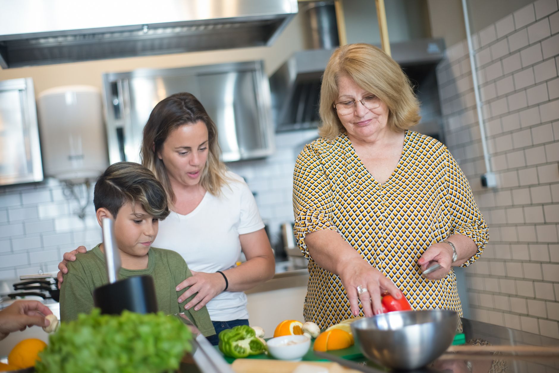 Three people preparing fresh vegetables during an interactive cooking class