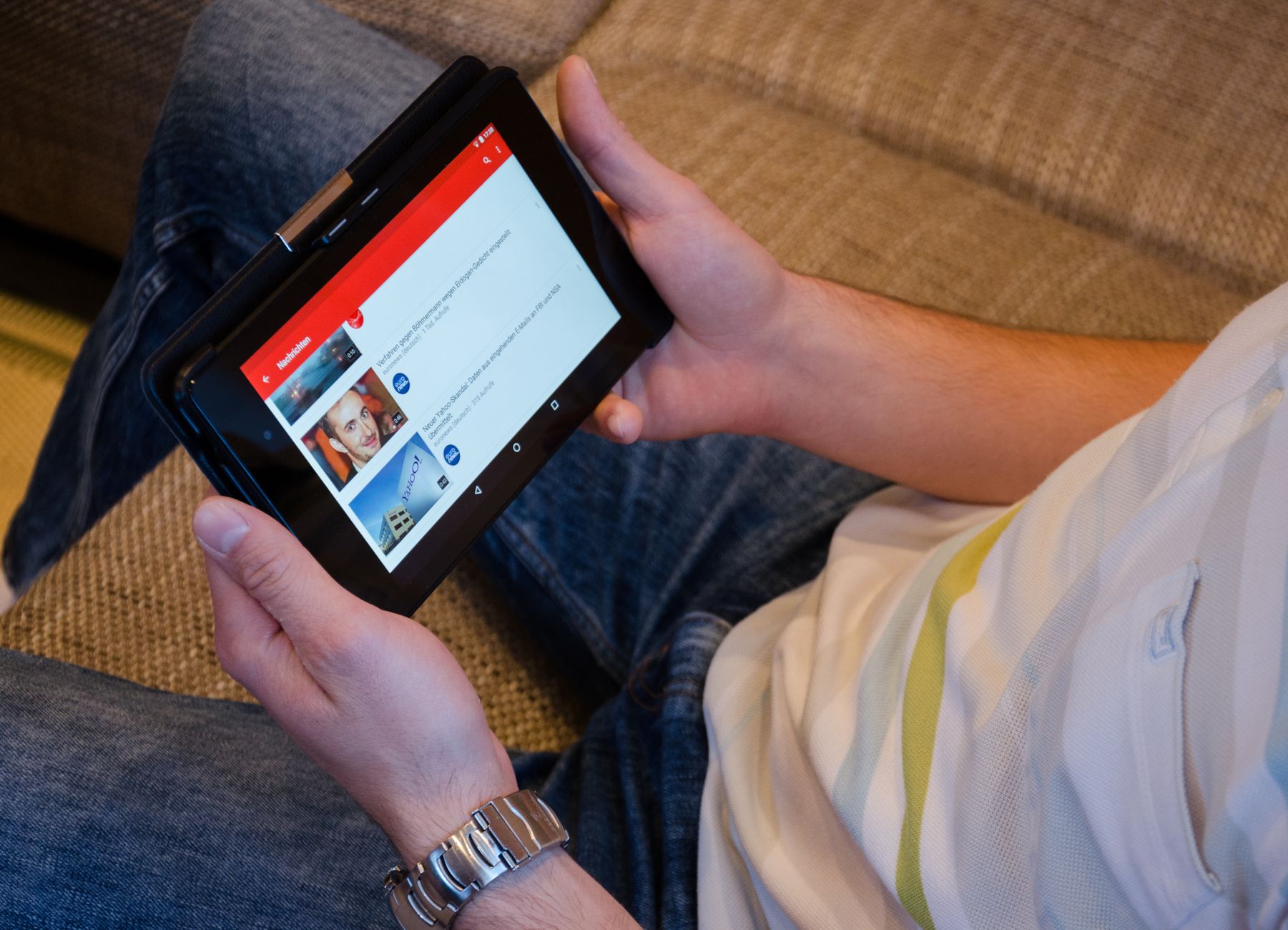 A person holding a tablet while browsing video content on the YouTube app
