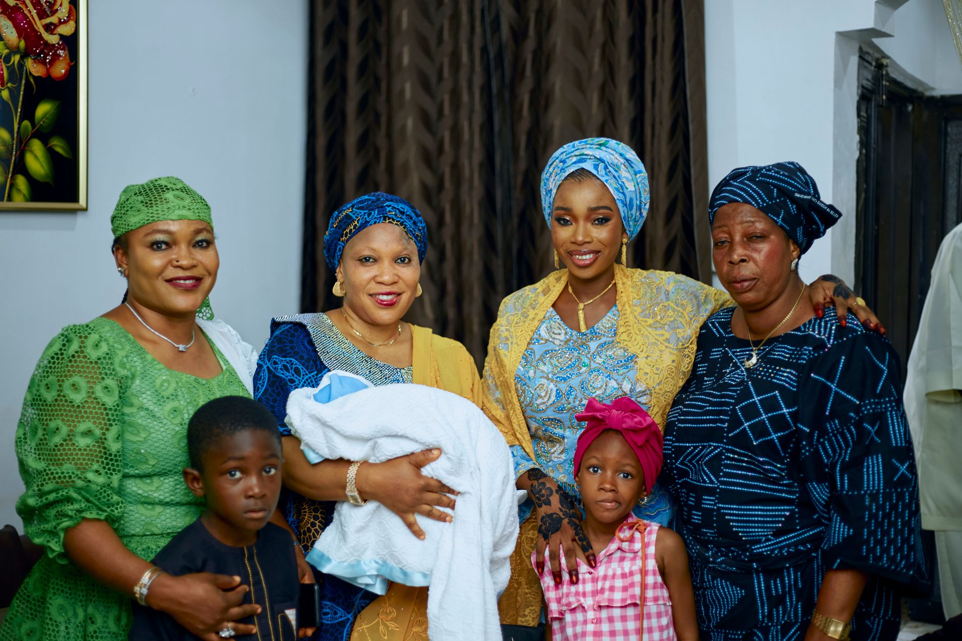 Several women and children with a baby wrapped in a blanket at a naming ceremony