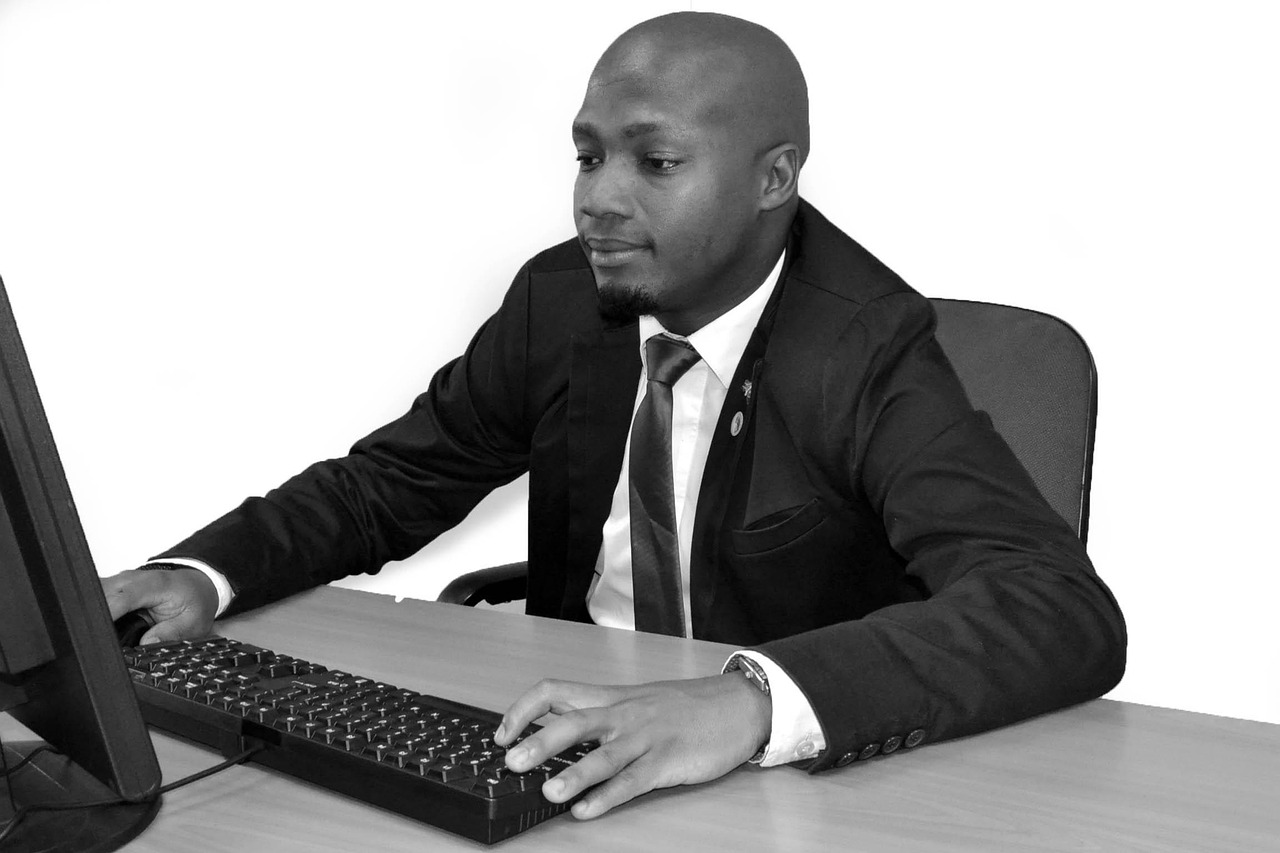 Black and white image of a man in a suit working at a computer
