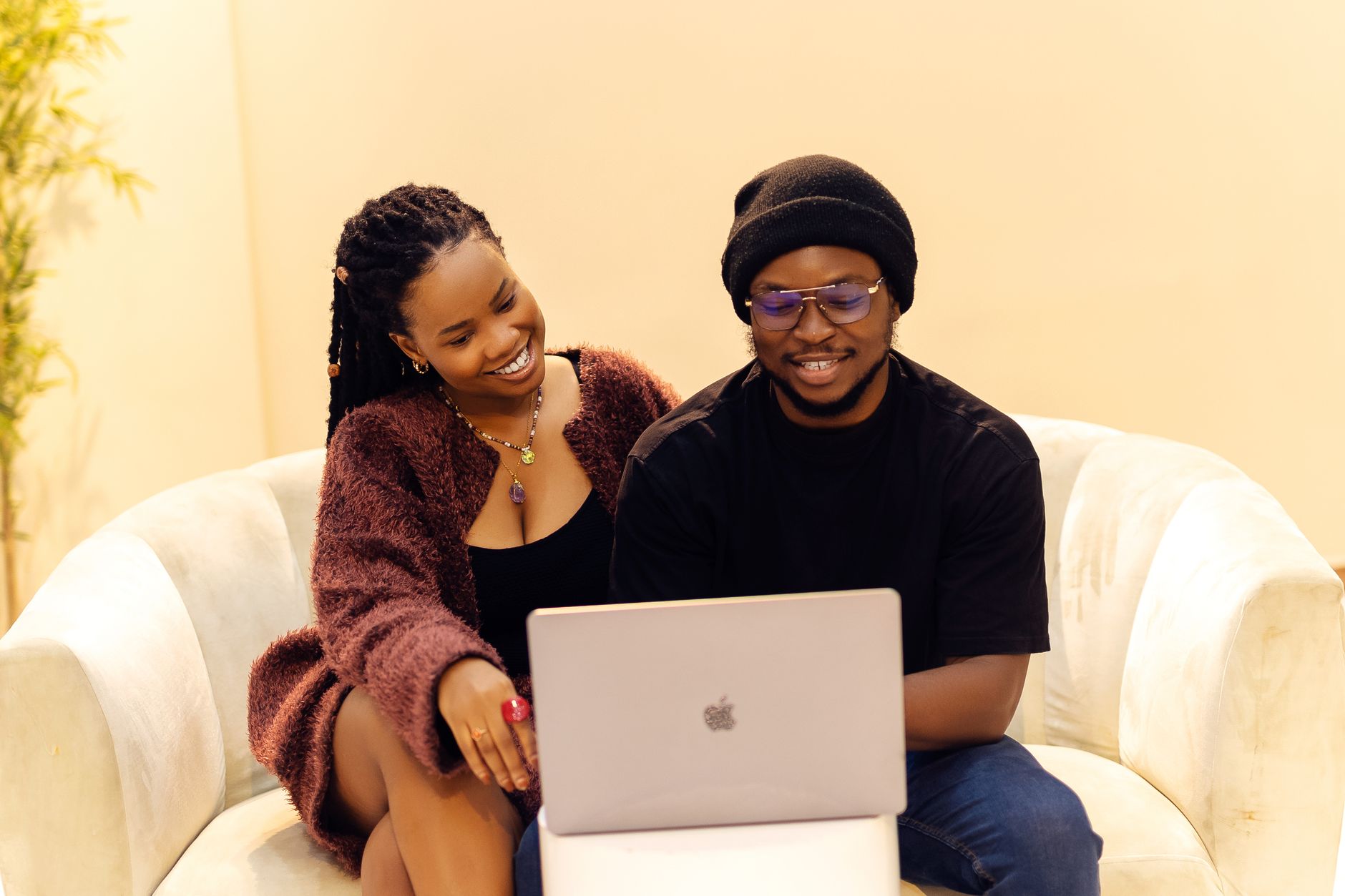 A smiling couple planning their wedding details together on a laptop