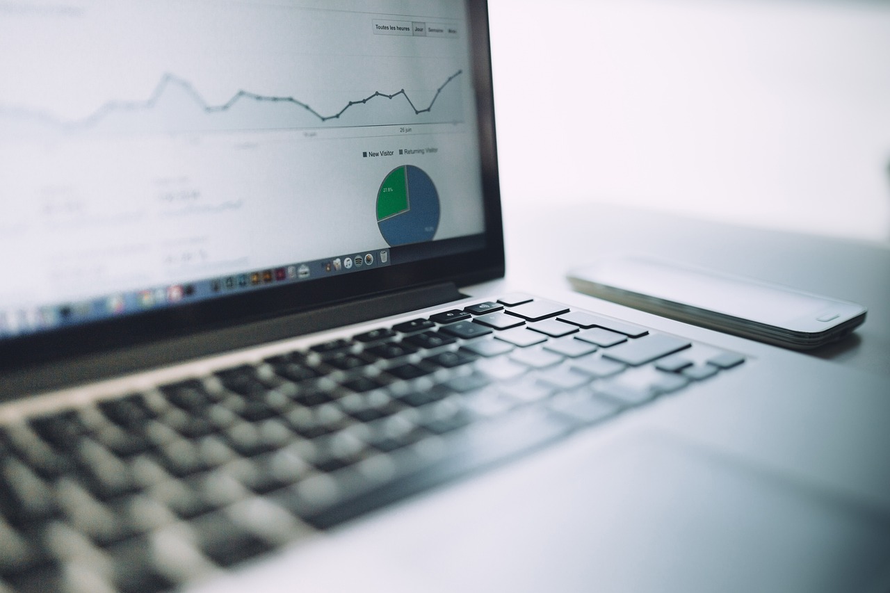 Laptop screen shows SEO performance graphs and pie charts, with a smartphone nearby