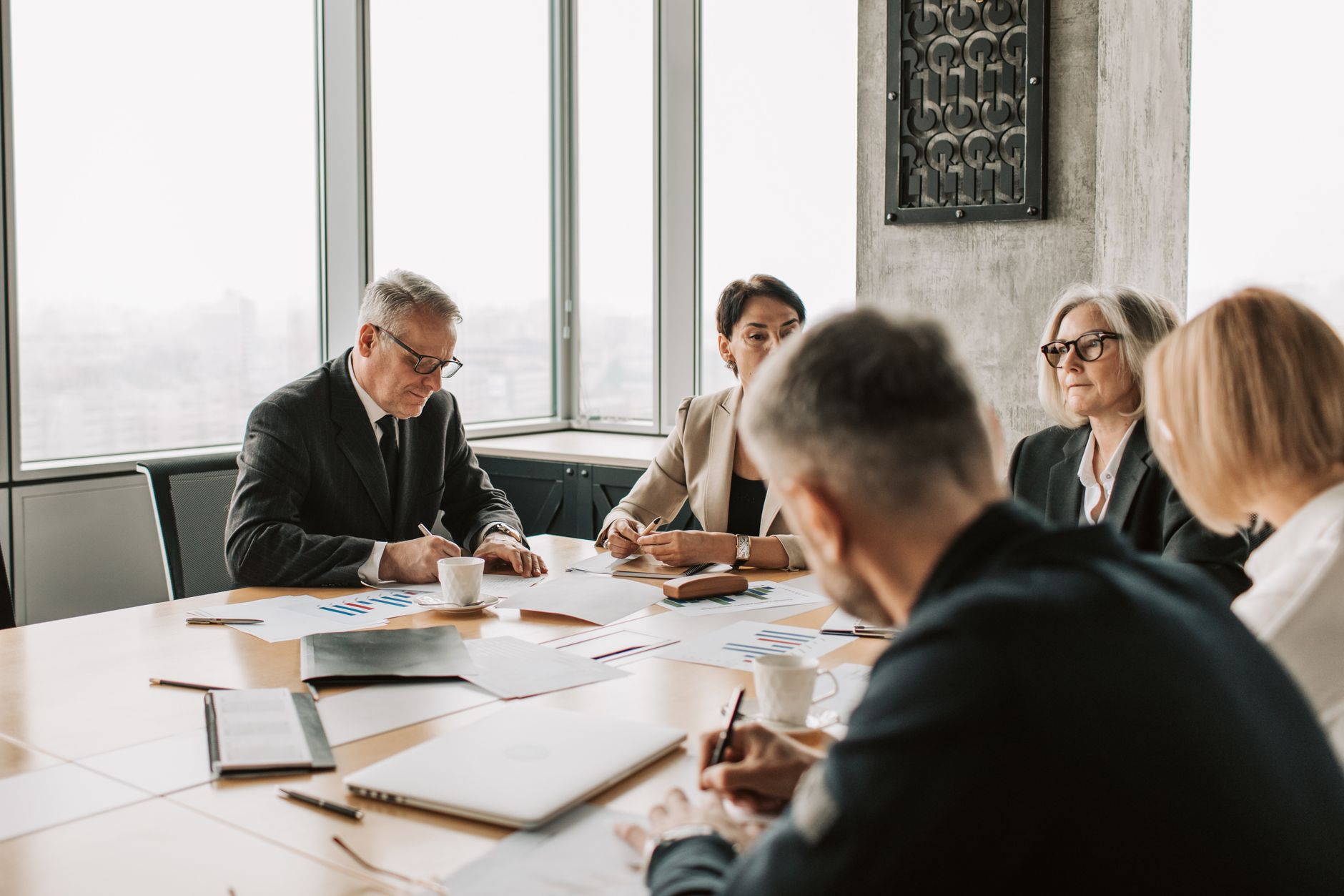 A group of business professionals meeting at a conference table with documents and charts