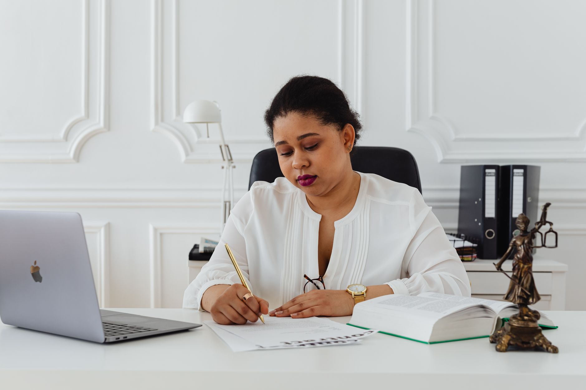 A female litigation lawyer reviewing a contract and legal documents at her desk